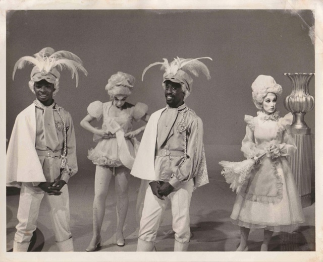 Bruce Heath and dancers are dressed in feather hats and elaborate costumes on the set of a 1970s television show